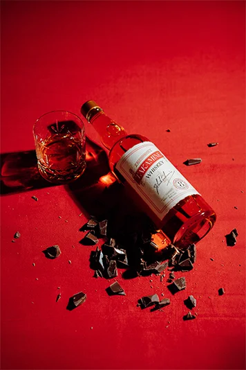 Takamine Whiskey bottle on red surface with chocolate shavings